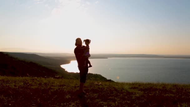 Papà e sua figlia si stanno godendo il tramonto sulla riva del lago di montagna. — Video Stock