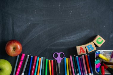 Tahtanın arka planında okul malzemeleri var. Okula geri dön.