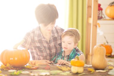 Cadılar bayramın kutlu olsun. Genç, güzel anne ve oğlu balkabağı oyuyor. Aile Cadılar Bayramı için hazırlanıyor.
