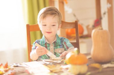Mutlu Cadılar Bayramı konsepti. Şirin küçük mutlu çocuk balkabağı oyuyor ve cadılar bayramı için dekore edilmiş kurabiyeler yapıyor..