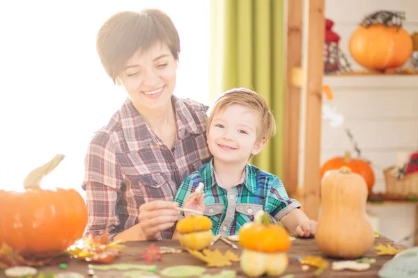 ハッピーハロウィン。若い美しい母親と彼女の息子はカボチャを彫る。ハロウィーンの準備家族. — ストック写真