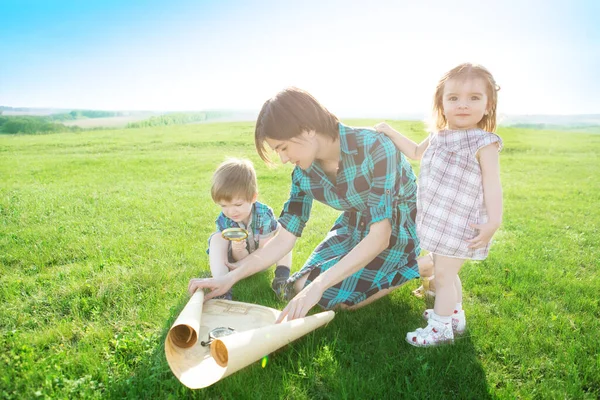 Diese Welt ohne Grenzen. Gehen Sie zu neuen Abenteuern und Entdeckungen. Eine schöne junge Mutter mit ihren Kindern blickt auf eine Weltkarte und entscheidet, wo sie eine Reise machen will. — Stockfoto