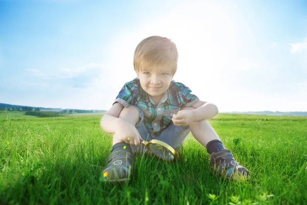 Молодий білий хлопчик вивчає сад в літній час зі своїм збільшувачем . — стокове фото