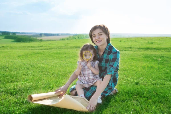 A beautiful young mother with her children looks at a map of the world and decide where to go on trip. — Stock Photo, Image