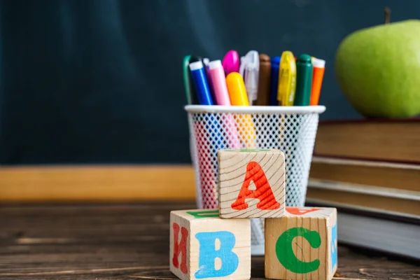 Livros e cubos com as letras ABC em mesa de madeira contra o fundo do quadro. De volta à escola — Fotografia de Stock