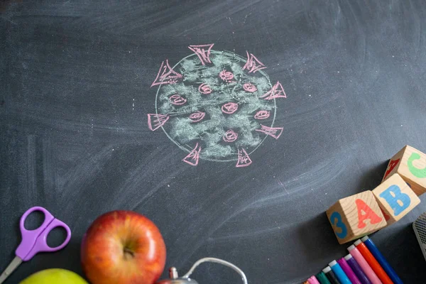 Chalk drawing of a virus COVID-19 on the background of blackboard. Back to school