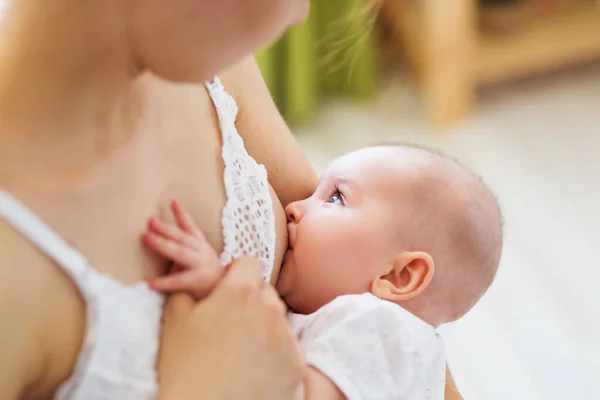 Jovem mãe mamando peito seu bebê no quarto — Fotografia de Stock