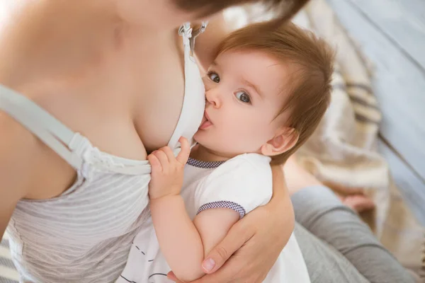 Mãe amamentando bebê em seus braços em casa. Mãe amamentando seu filho recém-nascido. Bebê comendo leite materno. Conceito de lactação infantil — Fotografia de Stock