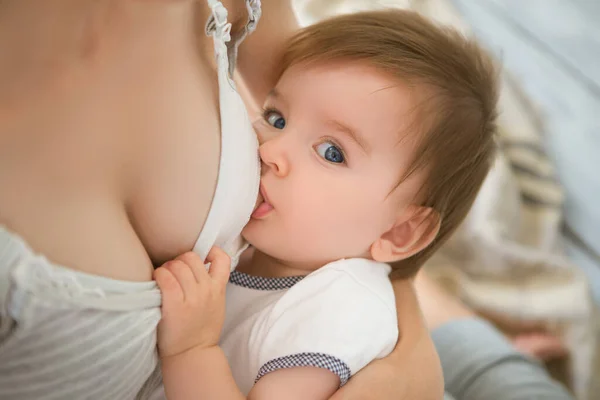 Mãe amamentando bebê em seus braços em casa. Mãe amamentando seu filho recém-nascido. Bebê comendo leite materno. Conceito de lactação infantil — Fotografia de Stock