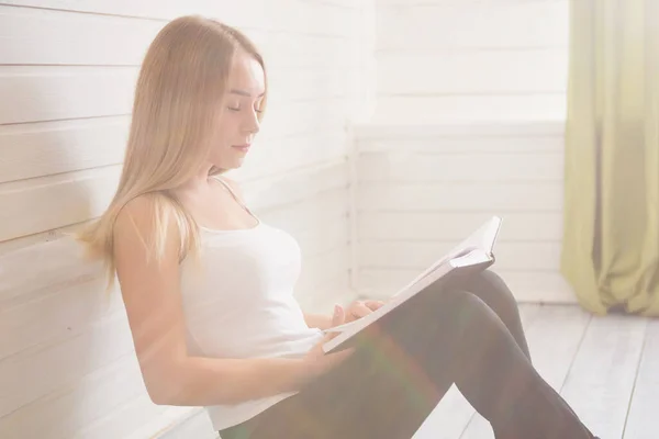 Mujer joven bastante hermosa leyendo libro cerca de la ventana en casa — Foto de Stock