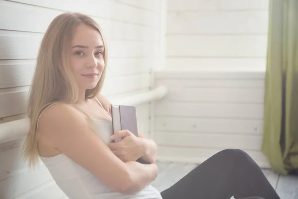 Studenten en onderwijs concept. Vrouw met boek op de houten witte vloer boven raam thuis — Stockfoto