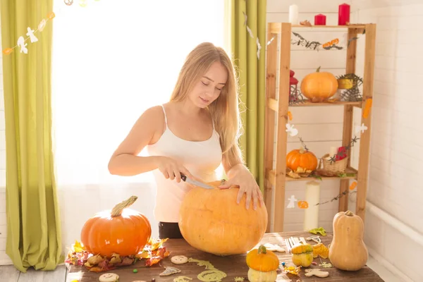 Happy Halloween. Young woman preparing for Halloween in the kitchen. Beautiful woman with pumpkins.