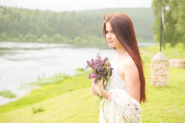 Mädchen mit Wildblumen auf Feld bei bewölktem Tag — Stockfoto