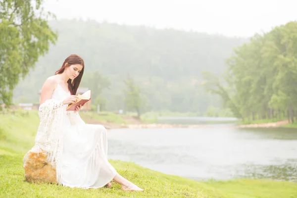 Mädchen im verregneten Park liest ein Buch — Stockfoto