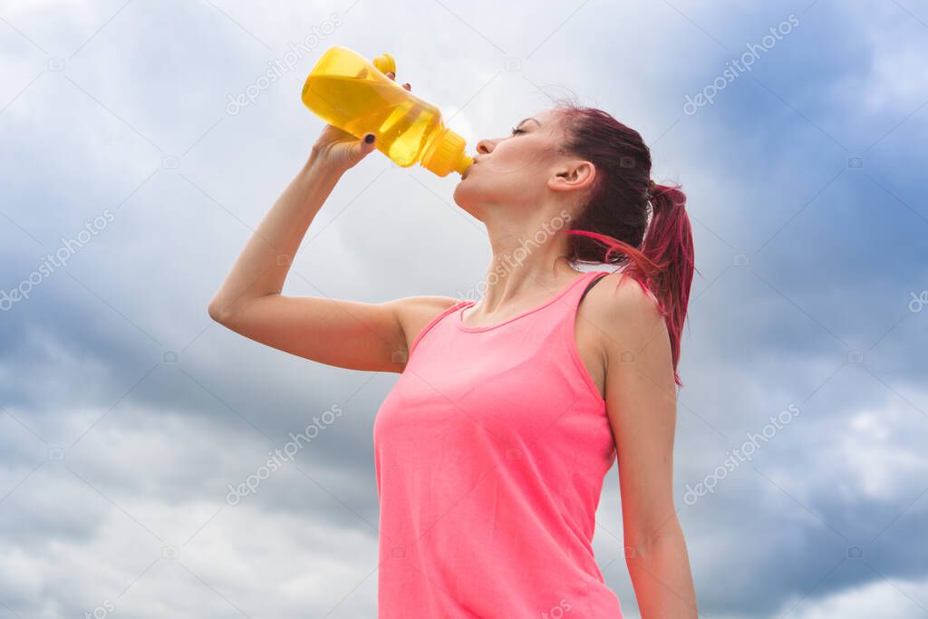 Girl drinks water against a sky after training. Healthy lifestyle.