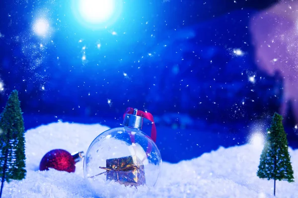 Weihnachten Hintergrund mit Weihnachtskugeln auf Schnee über Tanne, Nachthimmel und Mond. Geringe Schärfentiefe. Weihnachtlicher Hintergrund. Märchen. Makro. Künstliche magische Traumwelt — Stockfoto