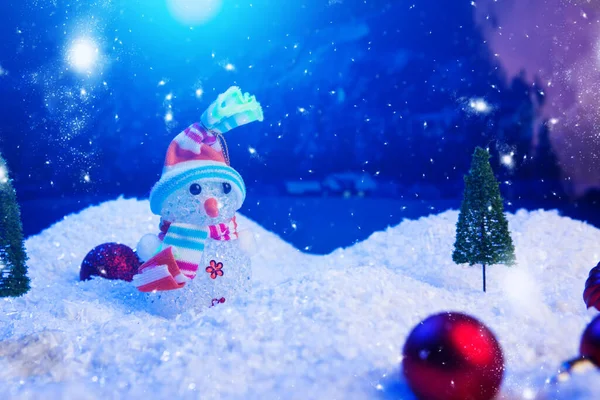 Schneemann mit Weihnachtskugeln auf Schnee über Tanne, Nachthimmel und Mond. Geringe Schärfentiefe. Weihnachtlicher Hintergrund. Märchen. Makro. Künstliche magische Traumwelt — Stockfoto
