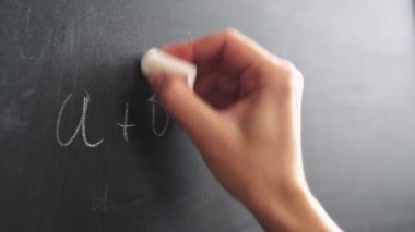 Tebeşirli kadın eli tahtaya bir formül yazar.