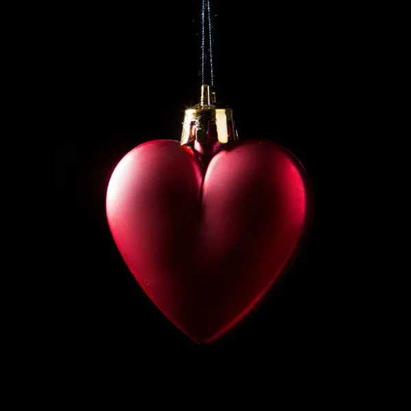 Bauble Natale rosso su sfondo scuro. Foto a basso profilo. Forma del cuore. — Foto Stock