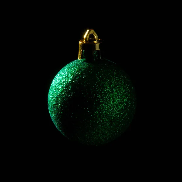 Bauble de Natal verde sobre fundo escuro. Fotografia discreta. Forma de bola. — Fotografia de Stock