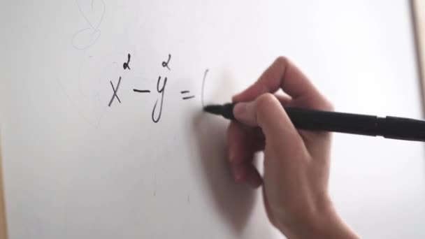 Weibliche Hand schreibt eine Formel mit einem Filzstift auf eine weiße Tafel — Stockvideo