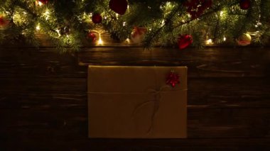 Tahta arka planda Noel hediyesi Köknar dalları ve çelenklerle