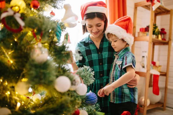 Feliz familia mamá e hijo en una mañana soleada de invierno de Navidad en una sala de celebración de Navidad decorada con un árbol de Navidad y regalos —  Fotos de Stock