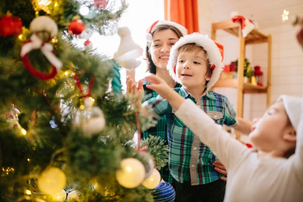Feliz familia mamá, hijo e hija en una mañana soleada de invierno de Navidad en una sala de celebración de Navidad decorada con un árbol de Navidad y regalos —  Fotos de Stock