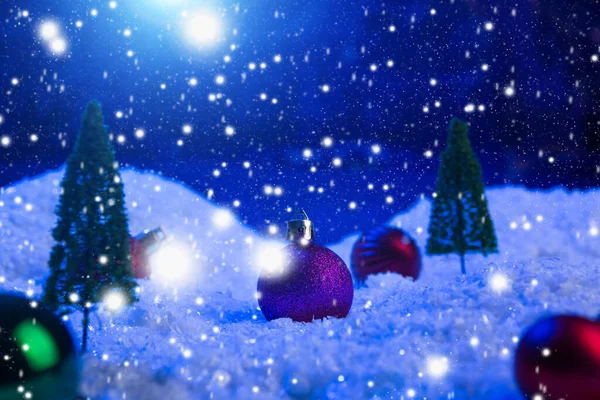 Weihnachten Hintergrund mit Weihnachtskugeln auf Schnee über Tanne, Nachthimmel und Mond. Geringe Schärfentiefe. Weihnachtlicher Hintergrund. Märchen. Makro. Künstliche magische Traumwelt. — Stockfoto