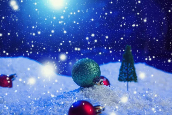 Fundo de Natal com bolas de Natal na neve sobre abeto, céu noturno e lua. Profundidade de campo rasa. Fundo de Natal. Conto de fadas. Macro. Mundo de sonho mágico artificial. — Fotografia de Stock