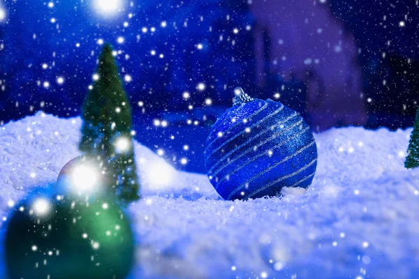Christmas background with Christmas balls on snow over fir-tree, night sky and moon. Shallow depth of field. Christmas background. Fairy tale. Macro. Artificial magic dreamy world. — Stock Photo, Image