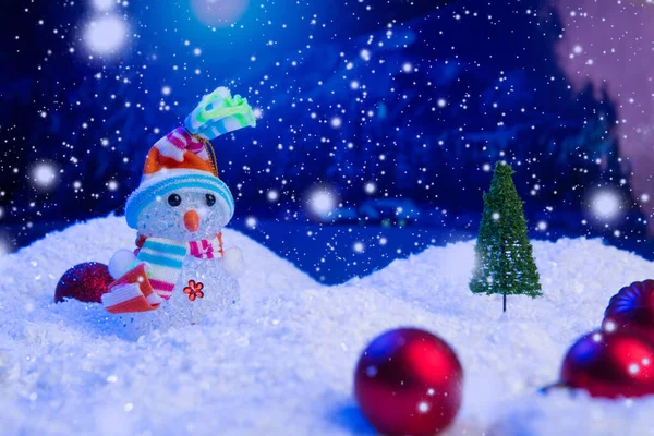 Schneemensch mit Weihnachtskugeln auf Schnee über Tanne, Nachthimmel und Mond. Geringe Schärfentiefe. Weihnachtlicher Hintergrund. Märchen. Makro. Künstliche magische Traumwelt. — Stockfoto