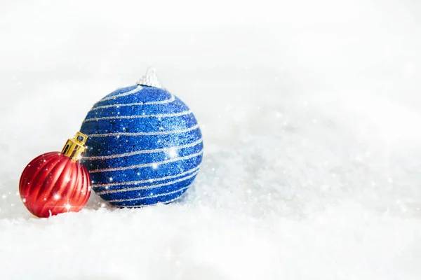 Χριστουγεννιάτικες μπάλες κόκκινες και μπλε σε αφηρημένο φόντο Όμορφα χριστουγεννιάτικα στολίδια στολίζουν το λευκό χνουδωτό χιόνι. Ατμόσφαιρα μαγείας και παραμυθιών — Φωτογραφία Αρχείου