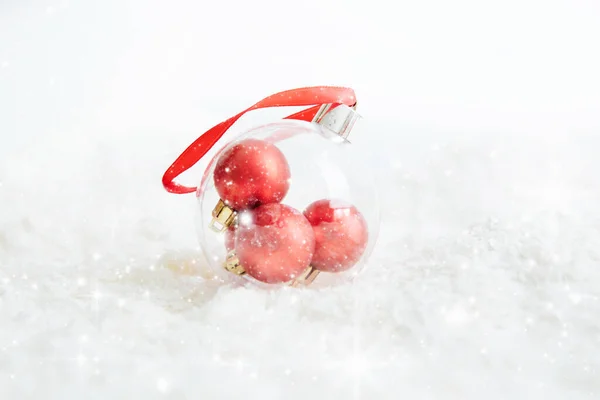 Transparent Christmas ball hanging on red ribbon on snowy winter background Beautiful Christmas bauble decorations lie on the white fluffy snow. Atmosphere of magic and fairy tales — Stock Photo, Image