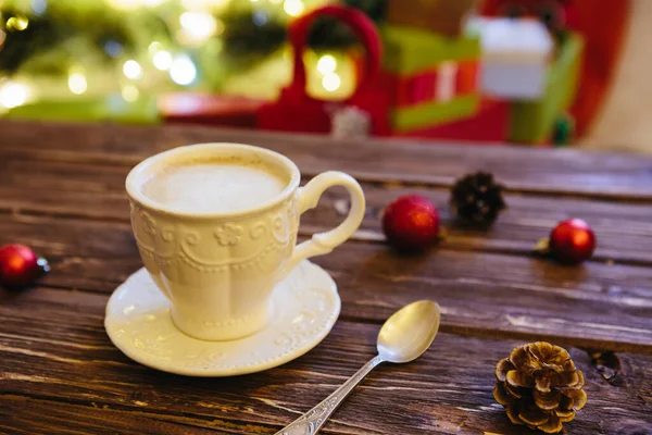 Κούπα με ζεστή σοκολάτα σε ξύλινο τραπέζι με χριστουγεννιάτικες διακοσμήσεις σε φόντο χριστουγεννιάτικου δέντρου — Φωτογραφία Αρχείου