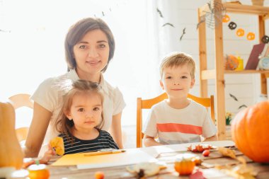 Mutlu aile Cadılar Bayramı için hazırlanıyor. Karnaval kostümlü genç anne ve çocukları bayramı kutluyorlar. Mutlu Cadılar Bayramı konsepti