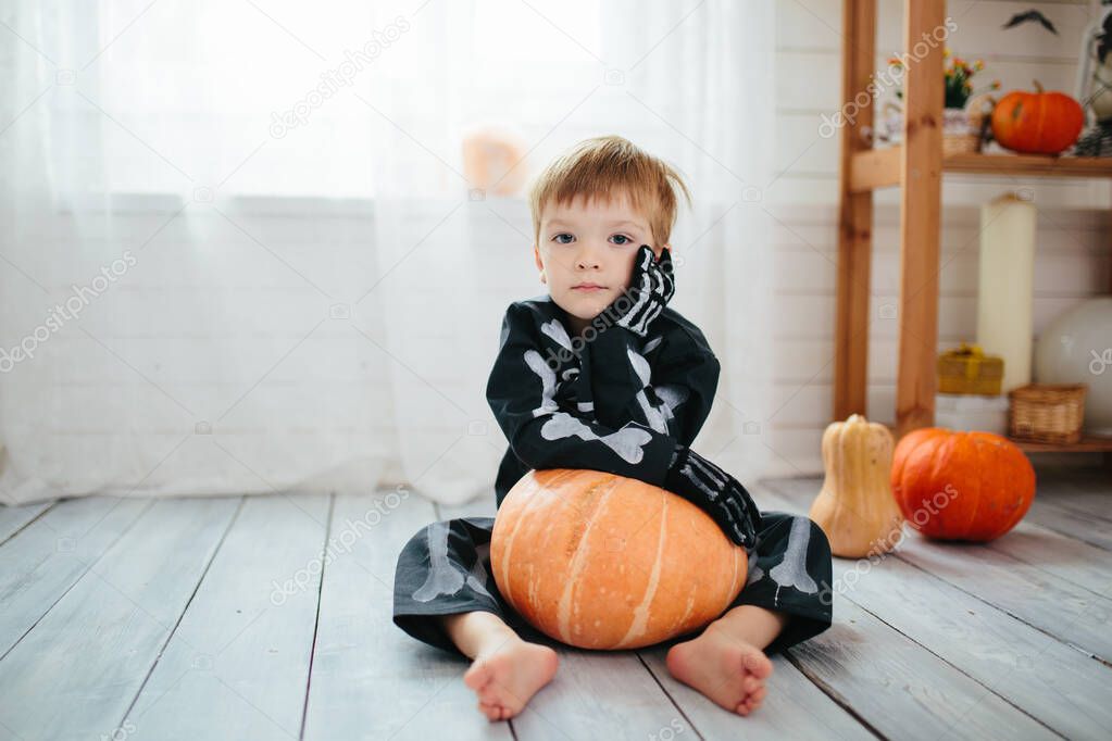 The little boy in a skeleton costume is ready to celebrate Halloween. Boy in a halloween dress-up room