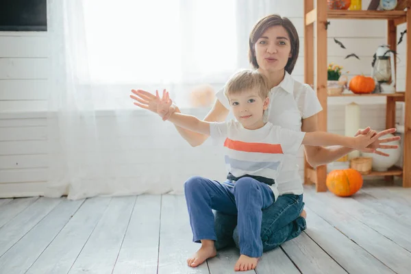 Mutter und ihr Sohn spielen im Halloween-Zimmer. Happy-Halloween-Konzept — Stockfoto