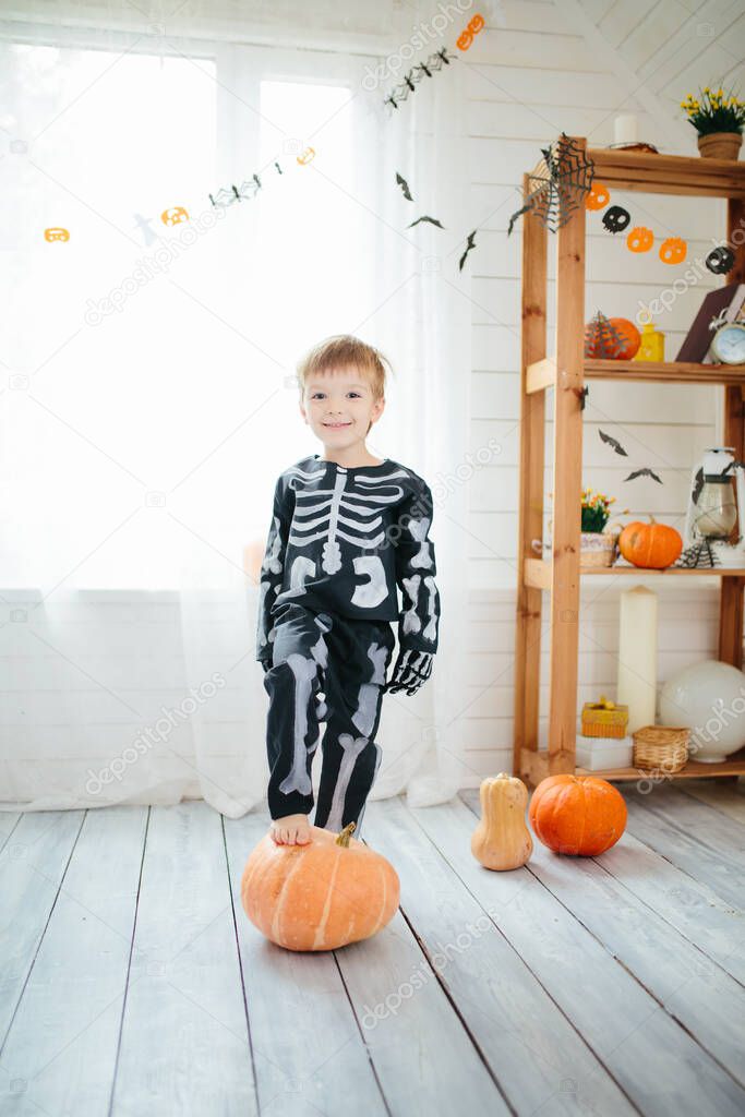 The little boy in a skeleton costume is ready to celebrate Halloween. Boy in a halloween dress-up room.
