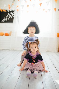 Korsan kostümlü bir oğlan ve cadı kostümlü bir kız Cadılar Bayramı 'nı evde kutluyor.