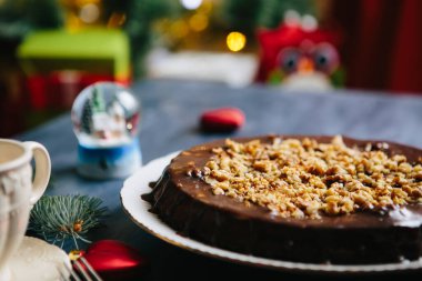 Noel masasında kır evleri ve zencefilli kurabiyeler Glüten ücretsiz Noel fındıklı kek gri bir masada Noel süslemeleri ile.