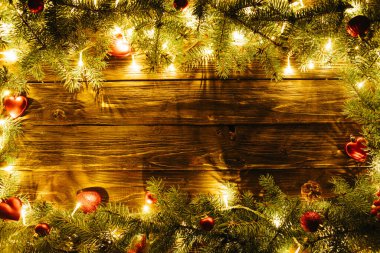 Noel ağacı, mücevher ve açık renk çelenk ile sınır çizimi Noel arkaplanı, köknar dalları, peri ışıkları ve kahverengi ahşap üzerine noel süslemeleri.