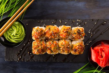 Siyah arka planda wasabi ve zencefilli fırında suşi ruloları. Japon Doğu mutfağı.