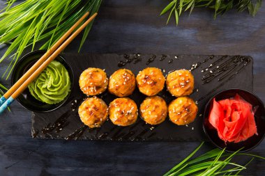 Siyah arka planda wasabi ve zencefilli fırında suşi ruloları. Japon Doğu mutfağı.