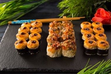 Siyah arka planda wasabi ve zencefilli fırında suşi ruloları. Japon Doğu mutfağı.