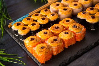 Siyah arka planda wasabi ve zencefilli fırında suşi ruloları. Japon Doğu mutfağı.