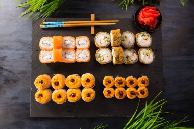 Siyah arka planda wasabi ve zencefilli fırında suşi ruloları. Japon Doğu mutfağı.