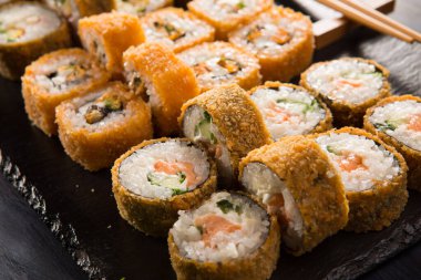 Siyah arka planda wasabi ve zencefilli fırında suşi ruloları. Japon Doğu mutfağı.