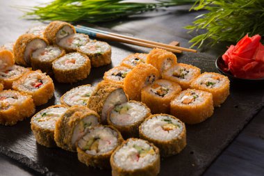 Siyah arka planda wasabi ve zencefilli fırında suşi ruloları. Japon Doğu mutfağı.