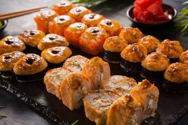Siyah arka planda wasabi ve zencefilli fırında suşi ruloları. Japon Doğu mutfağı.